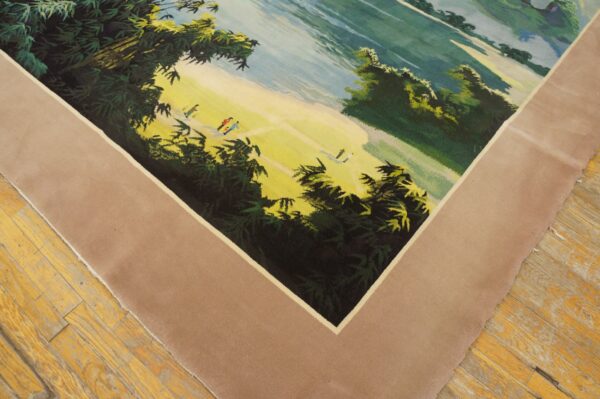 Low-pile rug with a green and yellow pictorial landscape and a wide solid beige border on wood flooring.