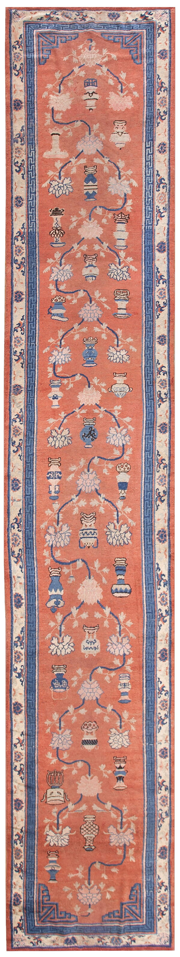 Coral runner rug with blue and white porcelain vessel and floral motifs and complex fretwork borders.