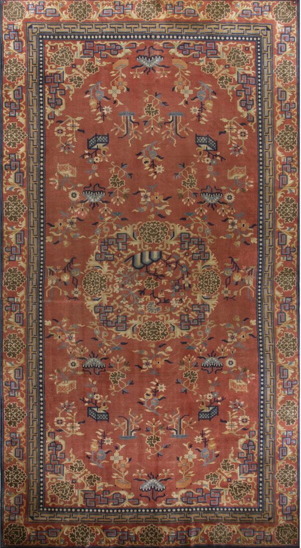 Red-orange rug featuring dense patterns of stylized flowers and vines outlined by blue borders.