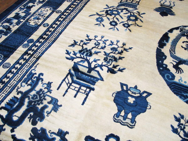 Detailed view of an ivory rug featuring complex blue traditional patterns, botanicals, and multiple ornate borders.