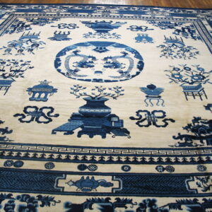 Ivory rug with indigo blue pictorial patterns of dragons and urns, framed by detailed borders on wood floor.
