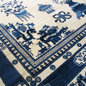 Cream and blue rug featuring a detailed corner with stylized dragons and a variety of geometric borders.