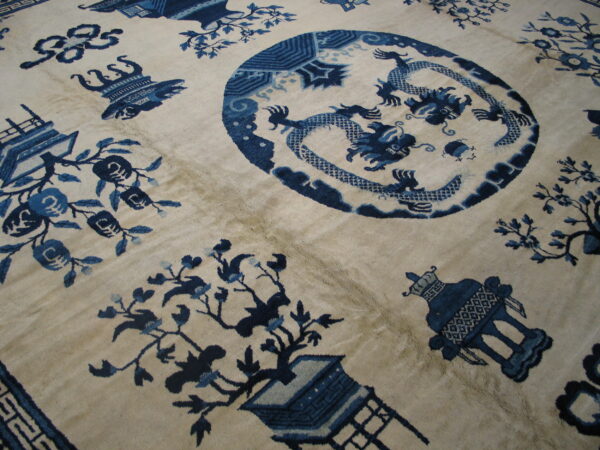 High-pile rug showing a cream background and detailed dark blue dragon, floral, and vessel motifs.
