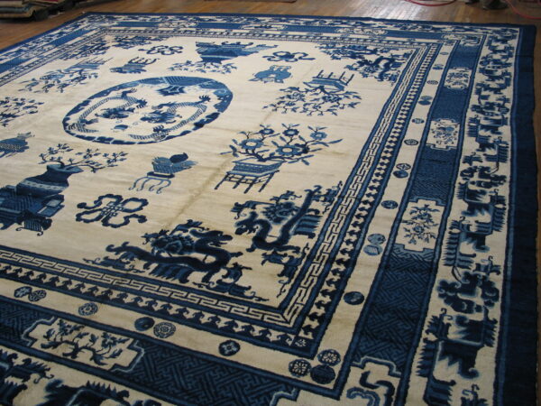 Large cream rug featuring a rich indigo chinese scenic and medallion pattern on wood flooring.