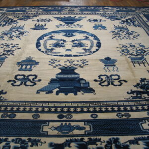 Blue and cream high-pile rug with Chinoiserie designs, including dragons and vases, displayed on a wood floor.