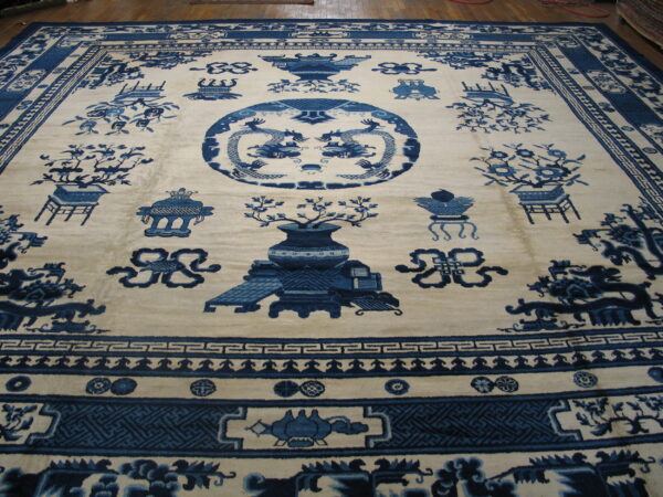 Blue and cream high-pile rug with chinoiserie designs, including dragons and vases, displayed on a wood floor.