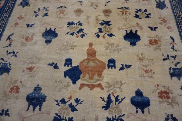 Light tan rug with blue and rust stylized vessels and botanicals, framed by a dark blue geometric border.