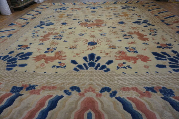 Cream rug featuring coral animal figures, blue floral designs, and wide patterned borders on wood flooring.