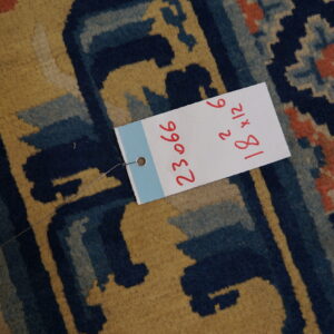 Close-up of a medium-pile rug displaying angular designs in mustard yellow, navy blue, and coral red.