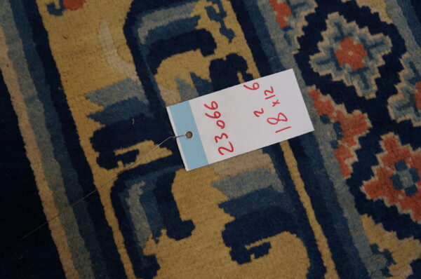 Close-up of a medium-pile rug displaying angular designs in mustard yellow, navy blue, and coral red.