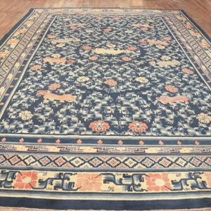 Navy blue rug with a coral and cream animal and floral pattern resting on a polished wood floor.