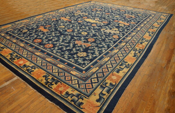 Navy blue rug with complex gold and orange floral and animal patterns lies angled on hardwood floors.
