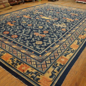 Navy blue rug with stylized mythical creatures and florals in coral and gold on a wooden floor.