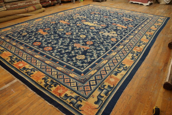Navy blue rug with stylized mythical creatures and florals in coral and gold on a wooden floor.