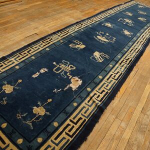 Long blue runner rug featuring tan motifs and a geometric border rests on rustic wood flooring.