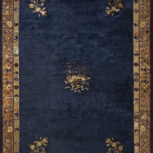 Navy blue rug with scattered gold floral elements and intricate tan and dark blue patterned borders.