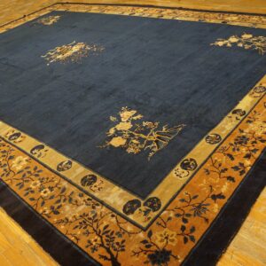 Dark blue rug features gold botanical motifs in the center field and detailed gold and navy floral borders on a wood floor.