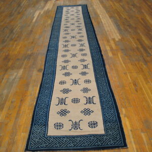 Runner rug with cream field, dark blue symbols, and teal geometric borders is on wood flooring.