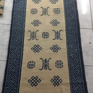 Beige runner rug with dark blue symbolic patterns and wide geometric borders on a white tile floor.
