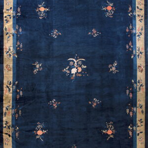 Deep navy rug with a wide beige border and stylized floral and grapevine patterns in pinks and blues.