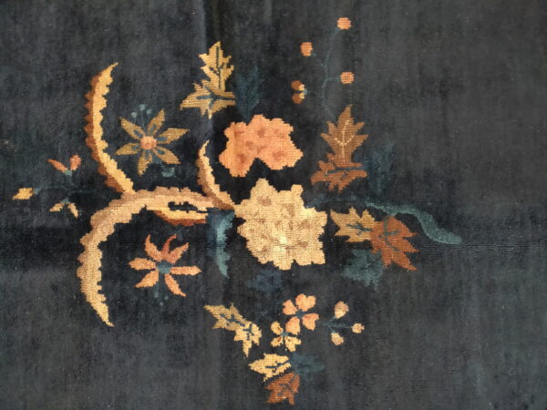 Deep blue rug featuring a vibrant gold, rust, and peach floral and leaf spray pattern.