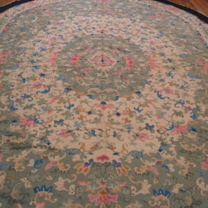 Circular rug with a pastel floral and scroll pattern in pink, blue, and sage green on a tan ground.