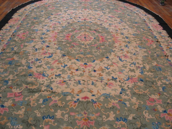 Circular rug with a pastel floral and scroll pattern in pink, blue, and sage green on a tan ground.