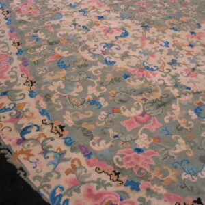 High-pile rug detailed with elaborate pink, blue, and tan floral scrolls on beige and sage fields.