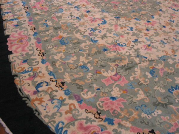 High-pile rug detailed with elaborate pink, blue, and tan floral scrolls on beige and sage fields.