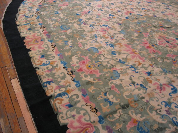 Ornate floral rug featuring pink, blue, and sage colors on a cream field with a black curved border.