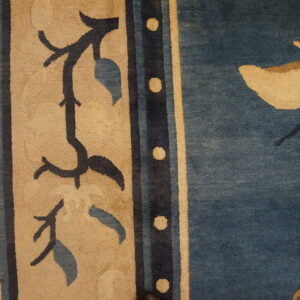 Beige border with dark floral vines next to a blue field featuring a large beige butterfly.