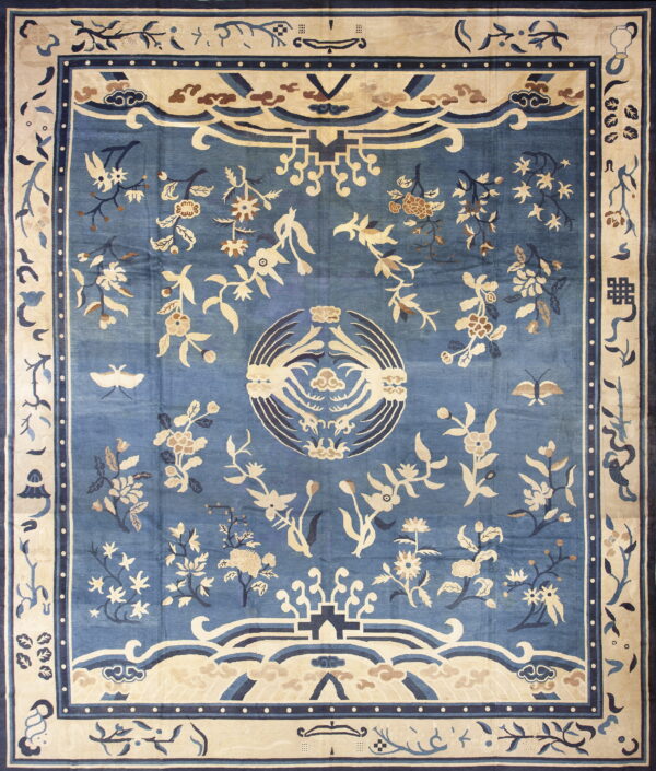 Light blue rug with extensive cream and tan botanical and avian motifs and a wide border.