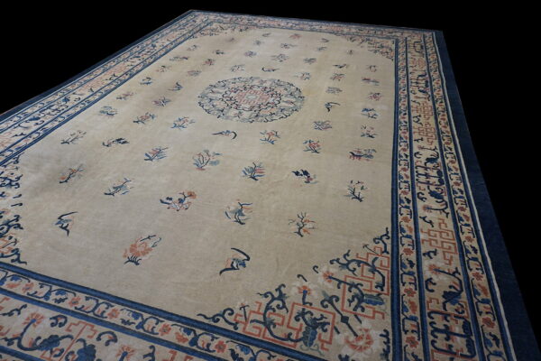 Beige low pile rug featuring scattered blue and coral floral motifs and intricate multi-layered borders.