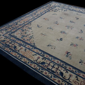 Tan rug with scattered blue and pink floral motifs and complex borders featuring navy and rust designs.