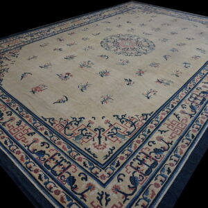 Large rectangular cream rug with scattered red and blue florals and detailed dark blue borders.