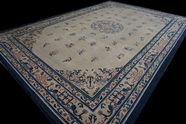 Large rectangular cream rug with scattered red and blue florals and detailed dark blue borders.
