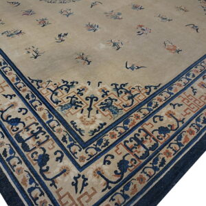 Low-pile tan rug featuring a scattered floral pattern and contrasting wide dark blue patterned border.