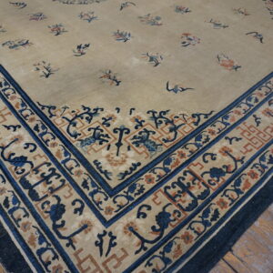 Close-up of a beige rug corner with scattered floral motifs and intricate blue and rust borders on wood floor.