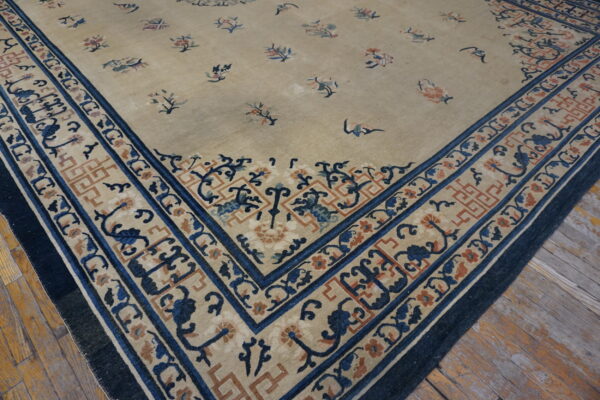 Close-up of a beige rug corner with scattered floral motifs and intricate blue and rust borders on wood floor.