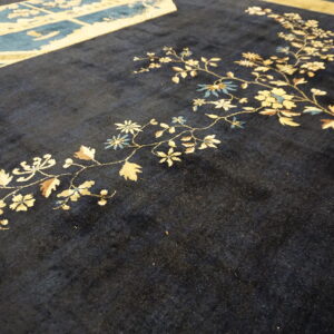 Dark blue rug field showing cream and pale blue floral vines next to a patterned blue border section.