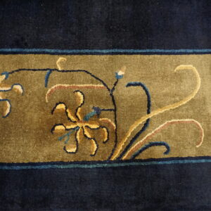 Navy blue and olive green rug detail featuring floral and vine motifs in cream and dark blue.