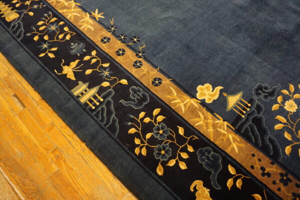 A detailed navy rug with gold borders, vines, and temple motifs is placed on wood plank flooring.