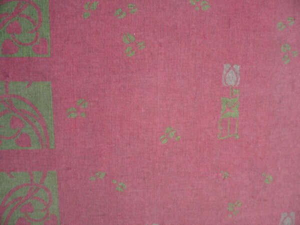 Flat woven textile detail in pink and green with stylized floral elements and geometric border squares.
