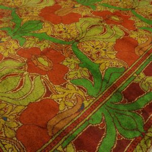 Vibrant red and lime green rug featuring a stylized large-scale floral and leaf pattern on wood floors.