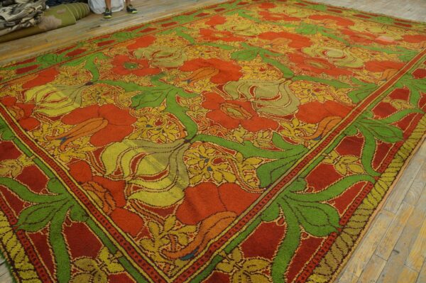 Vibrant orange rug with large green and yellow botanical patterns on light wood planks.