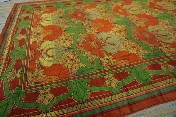 Red and orange rug with large green and gold botanical patterns on a weathered wood floor.