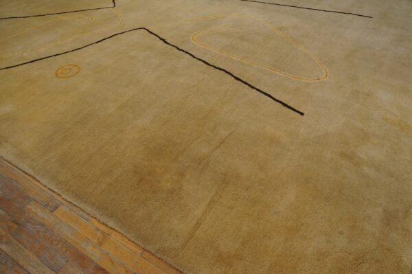 Vintage large size modernist mid century modern ecuadorian art rug 6 A golden beige rug with abstract dark brown and yellow designs lies on worn wood floors.