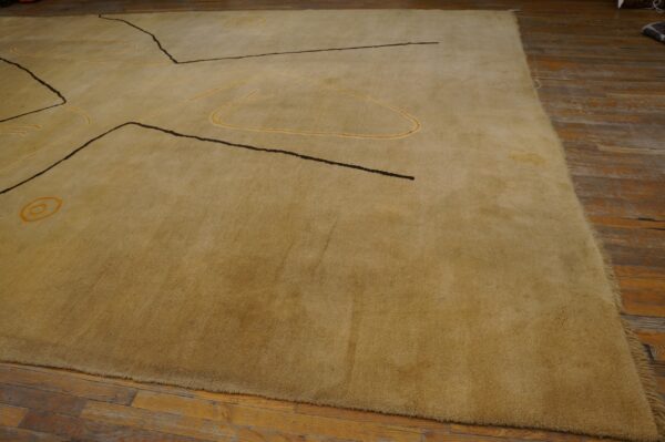 Vintage large size modernist mid century modern ecuadorian art rug 5 A textured tan rug with abstract black and gold linear designs rests on distressed hardwood.