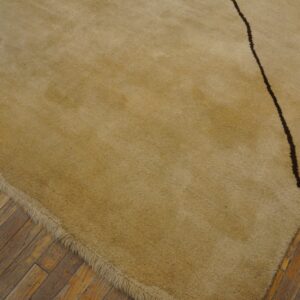 High-pile beige rug with a dark curving line resting on aged wooden floorboards.