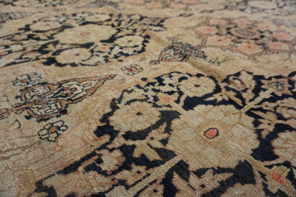 Distressed low-pile rug texture featuring an intricate pattern in beige, black, and subtle coral.